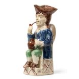 A Creamware ''Thin Man'' Toby Jug, circa 1780, seated wearing a manganese tricorn hat, blue jacket