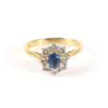 An 18 Carat Gold Sapphire and Diamond Cluster Ring, an oval cut sapphire in a claw setting within