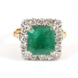 An Emerald and Diamond Cluster Ring, a square octagonal cut emerald in a claw setting, within a