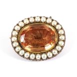 A Circa 1820 Topaz and Seed Pearl Brooch, an oval cut foil backed golden topaz in a collet