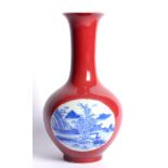 A Chinese Porcelain Bottle Vase, painted in underglaze blue with river landscapes on a coral ground,