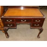 An Early 20th Century Carved Mahogany Desk, with inset brown leather writing surface above an