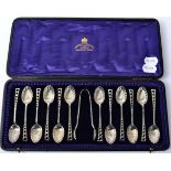 A set of twelve Edwardian silver teaspoons and tongs, Atkin Bros, Sheffield 1905, with scalloped