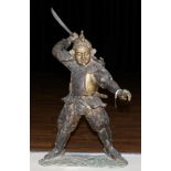 A Japanese Bronze Figure of a Samurai, Meiji period, standing holding a short sword in his raised