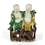 A Chinese Porcelain Figure Group, Kangxi, as two children sitting on a rocky outcrop decorated in