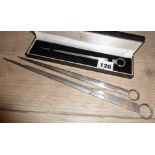 One cased solid silver and two silver-plated meat skewers