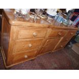 Victorian pine dresser base having seven drawers flanking single cupboard door, 6' long x 3'1"