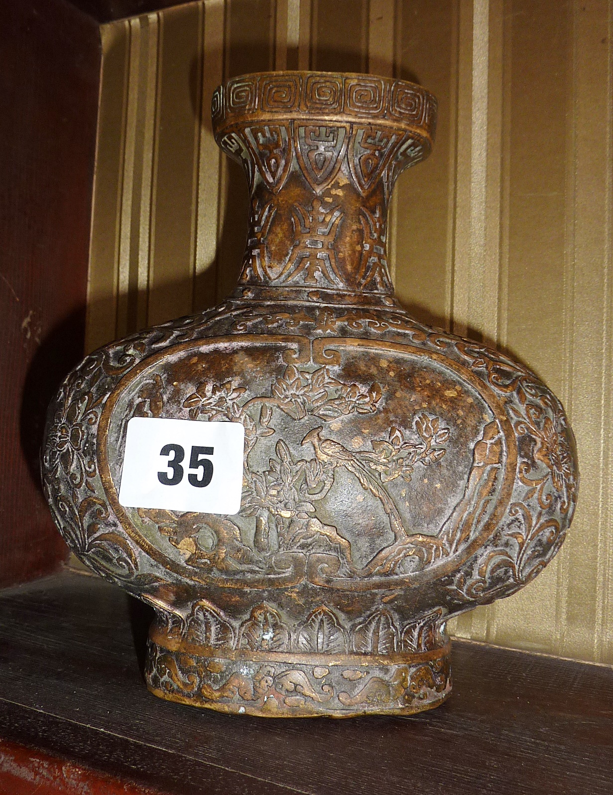 A Chinese bronze vase decorated with relief birds and flowers - stamped to base, approx 17cm high