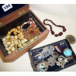 Assorted jewellery and enamel badges in an old box, including cherry amber bakelite beads, scrap