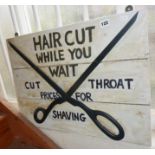 Painted wood barber's sign reading "Haircut while you wait - cut throat prices for shaving"