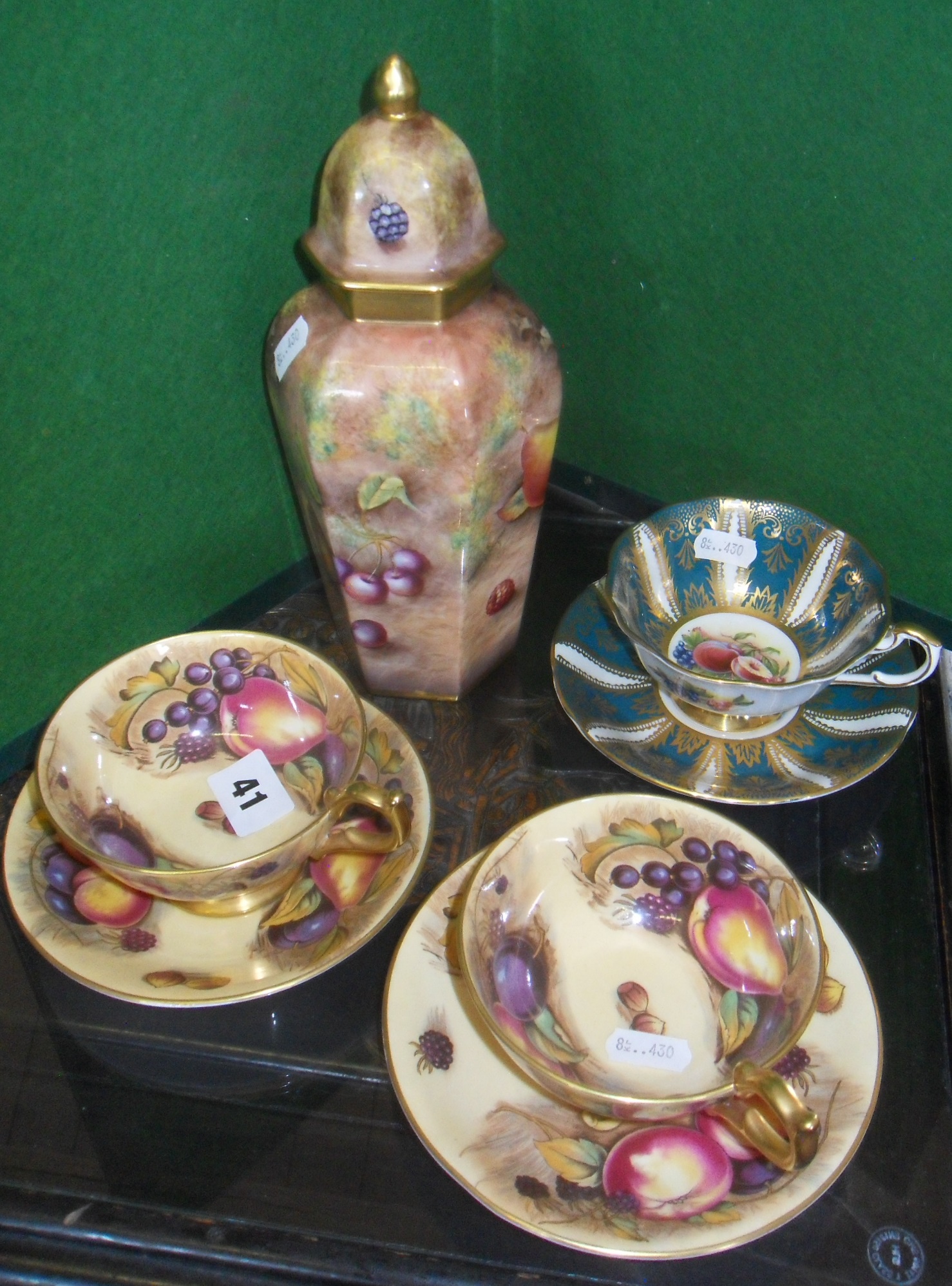 Pair Aynsley china tea cups and saucers with fruits decoration, a similar lidded vase hand painted