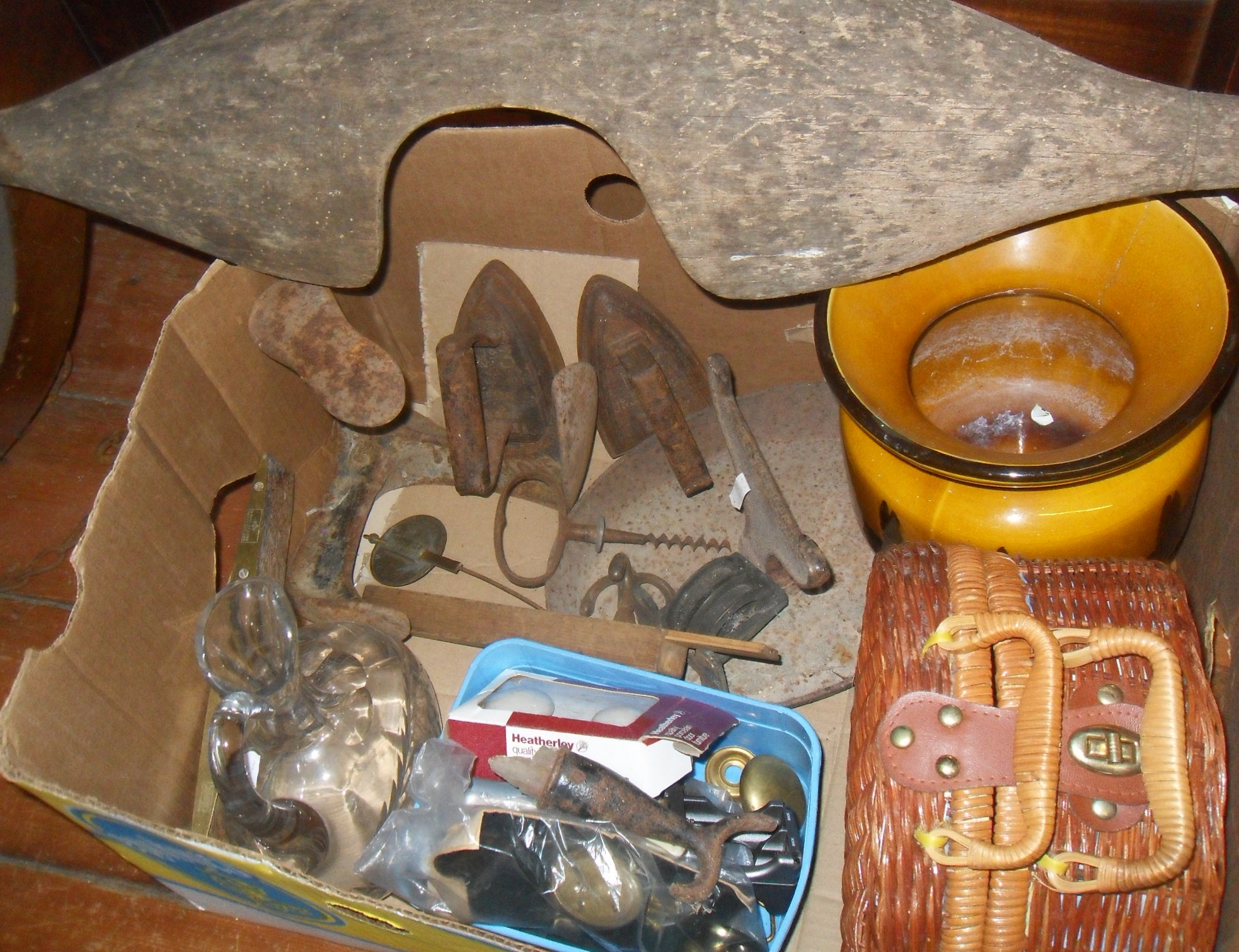 Box of assorted metalware, inc. cast iron boot scraper, flat irons, tools and an old wooden yoke