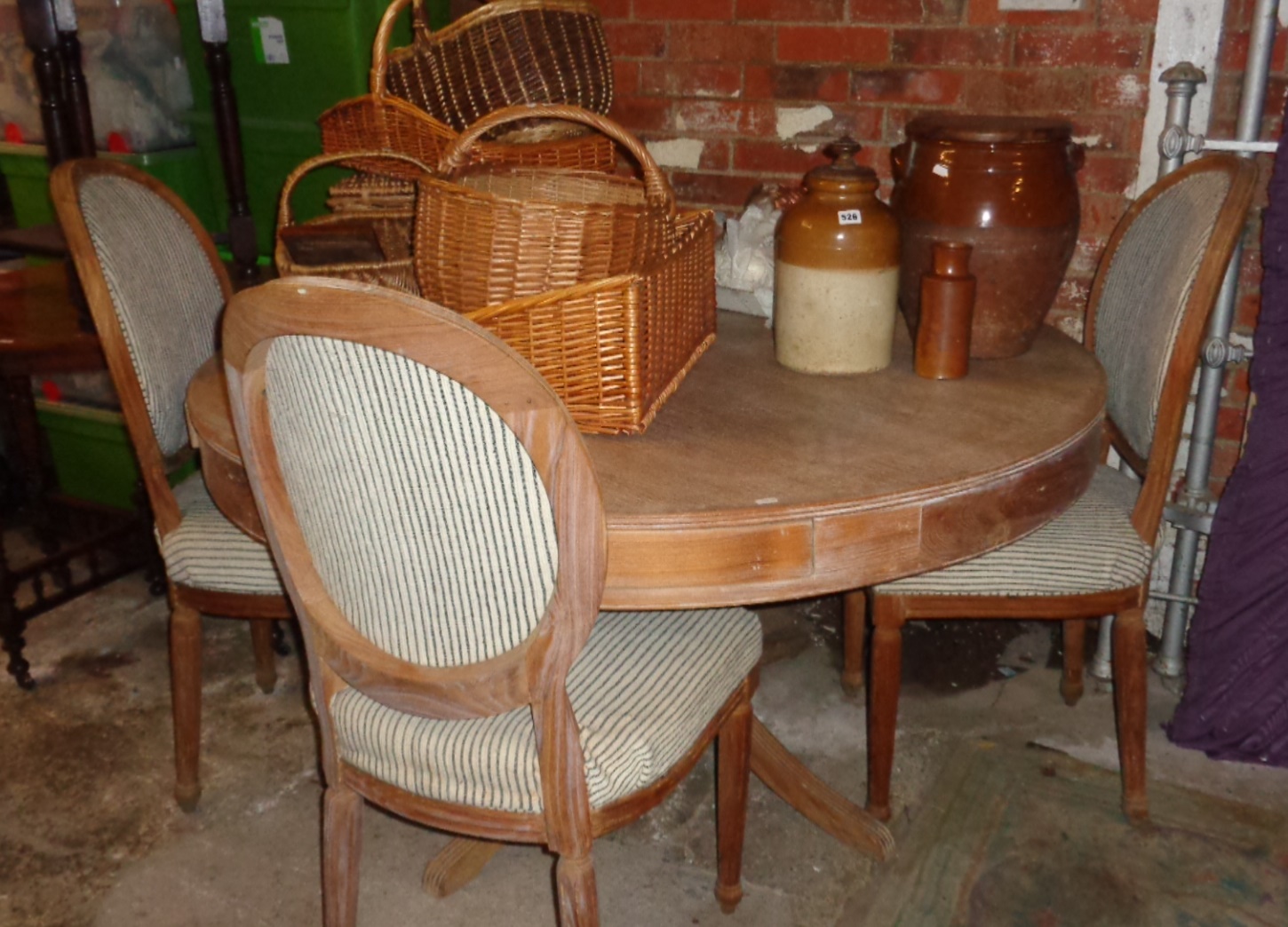 Large circular pine dining table with drawers and a set of four similar upholstered dining chairs
