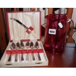 Cranberry coloured glass jug and a cased set of grapefruit spoons and knife