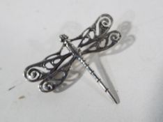 A silver brooch in the form of a dragonfly.