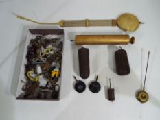 A box containing a quantity of mixed clock accessories including weights, pendulums,