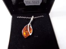 A silver pendant and chain, stone set with amber.