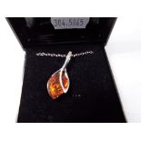 A silver pendant and chain, stone set with amber.