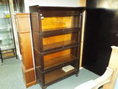An early 20th century oak four section office bookcase with hinged glass front,
