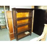 An early 20th century oak four section office bookcase with hinged glass front,