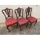 Three Chippendale style dining chairs with pierced and carved back splats,