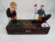 A cast iron mechanical money bank in the form of a golfer and a caddy - This lot MUST be paid for