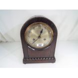 An oak cased mantel clock, Arabic numerals on a silvered dial,