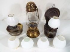 A small brass oil lamp, two further oil lamps and four additional miniature glass shades.