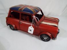A tin-plate car in the form of a Mini, approximate height 15 cm x 32 cm (l).