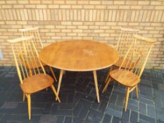 An Ercol light elm gate-leg drop-leaf dining table with two Ercol carver chairs and two matching