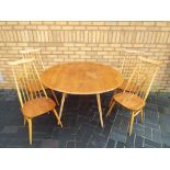 An Ercol light elm gate-leg drop-leaf dining table with two Ercol carver chairs and two matching