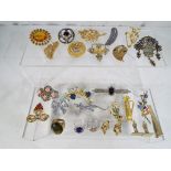 A wooden box containing nineteen decorative brooches, three rings, a pair of earrings,