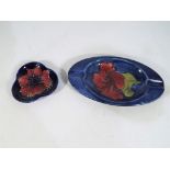 Moorcroft Pottery - a Moorcroft Pottery oval ashtray decorated in the Hibiscus pattern on a blue