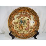 A large Japanese ceramic charger depicting three Geisha in a garden scene,