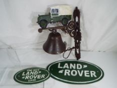 A cast iron bell and two advertising wall plaques depicting Landrover (3).