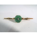 A hallmarked 18 carat gold bar brooch set with a hard stone in the form of a flower and a