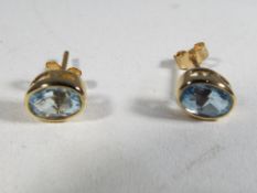 A pair of 9 carat gold and oval cut topaz stud earrings.