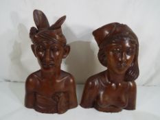 A pair of Klungkung, Bali carved teak wood busts depicting a native male and female,