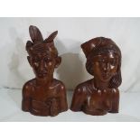 A pair of Klungkung, Bali carved teak wood busts depicting a native male and female,
