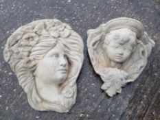 A wall mounted stone planter in the form of a cherub's face and a wall mounted plaque depicting a