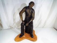 A large hot cast bronze sculpture depicting a man seated on a log, ca 1998,