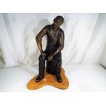 A large hot cast bronze sculpture depicting a man seated on a log, ca 1998,