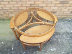 A Vintage Danish teak wood retro glass top circular coffee table housing three side tables,
