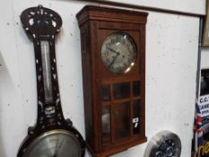 An oak cased wall clock having Arabic numerals to the silvered dial, with pendulum and key,