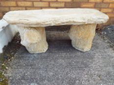 A large stone bench in the form of a tree trunk,