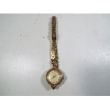 A lady's 9 carat gold wristwatch on a 9 carat gold strap,