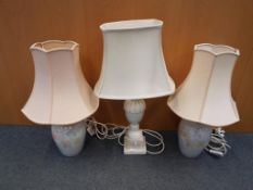 A pair of ceramic based table lamps decorated flowers and butterflies and a further table lamp with