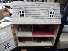 A three storey furnished dolls house with opening roof and one opening front panel to reveal the
