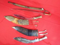 Two Kukri knife sets both contained in scabbards and an Indian sabre type blade with brass grip and