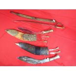 Two Kukri knife sets both contained in scabbards and an Indian sabre type blade with brass grip and